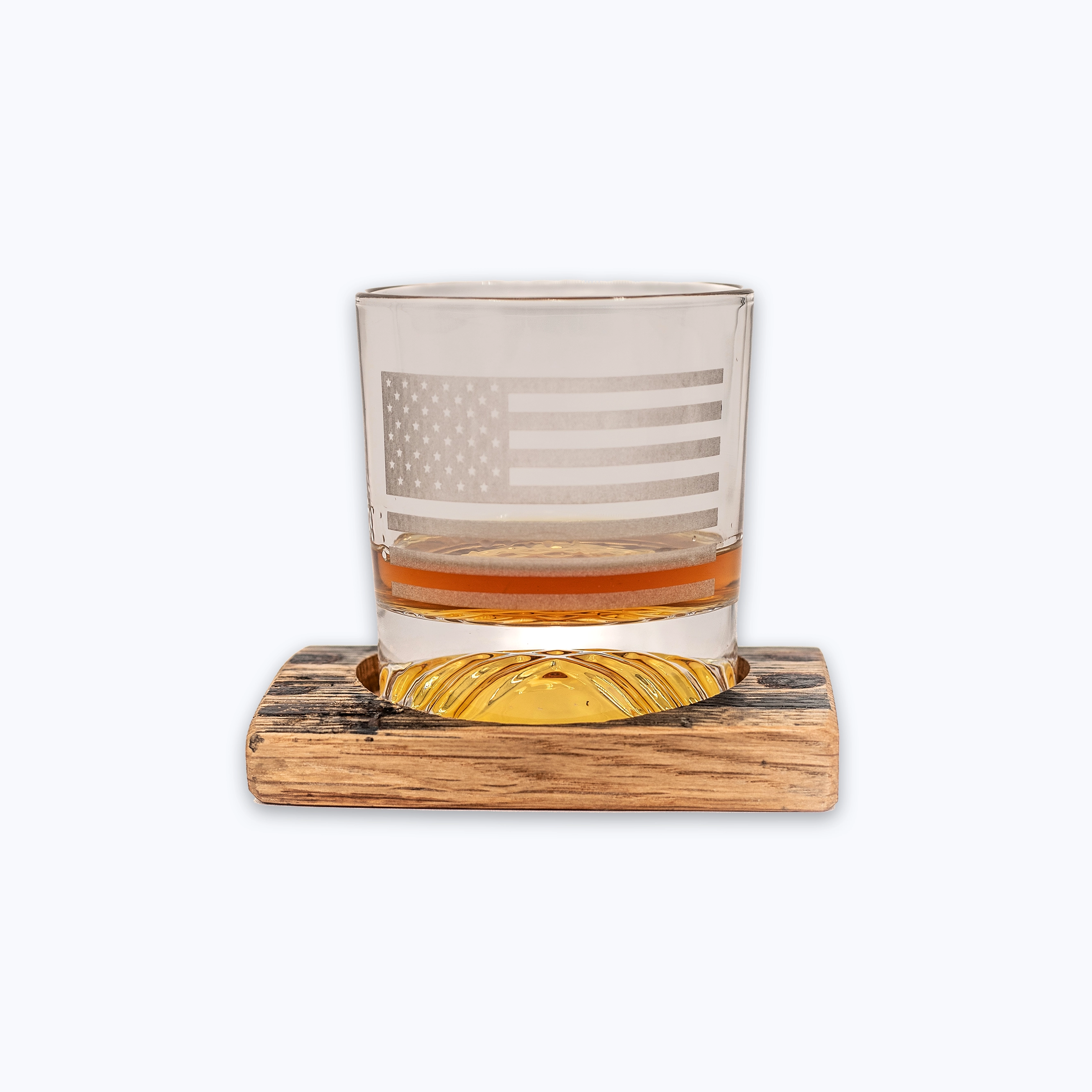 Rocks glass with American flag design on a bourbon barrel wooden coaster