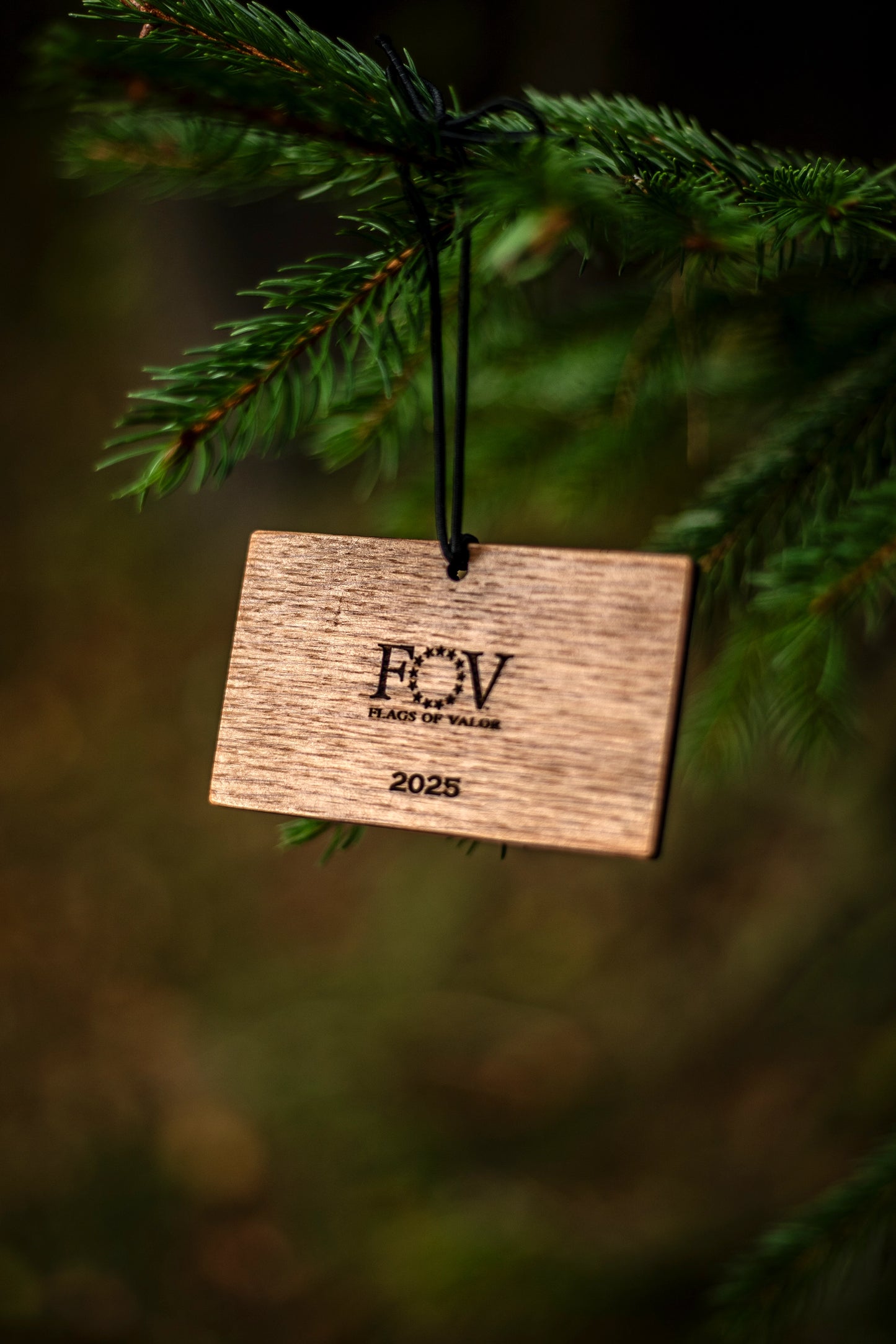 Backside of wooden bourbon barrel ornament with 'FOV' and '2025' text hanging on a tree branch.