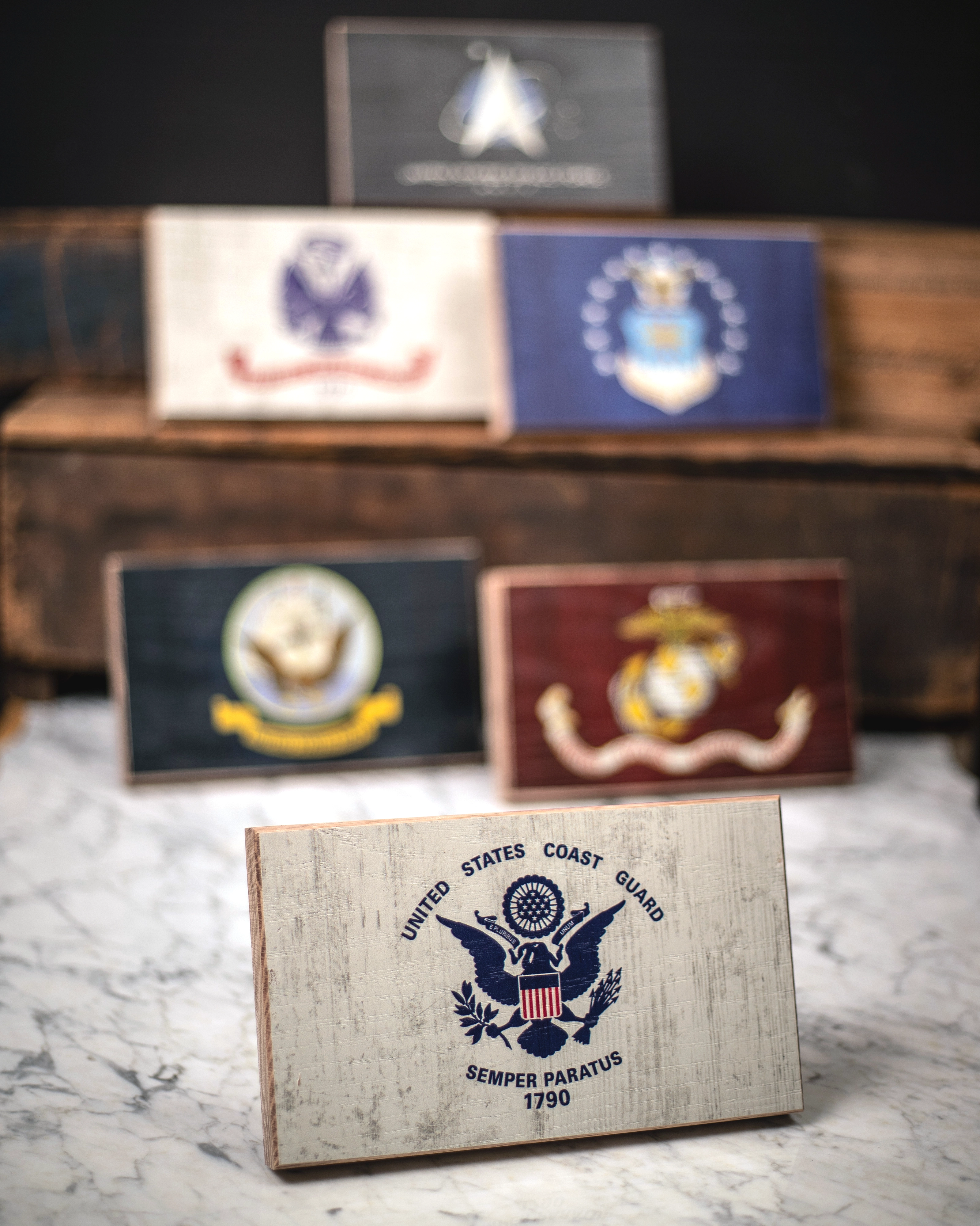 Collection of U.S. military service branch desk flags featuring U.S. Coast Guard sitting on marble surface.