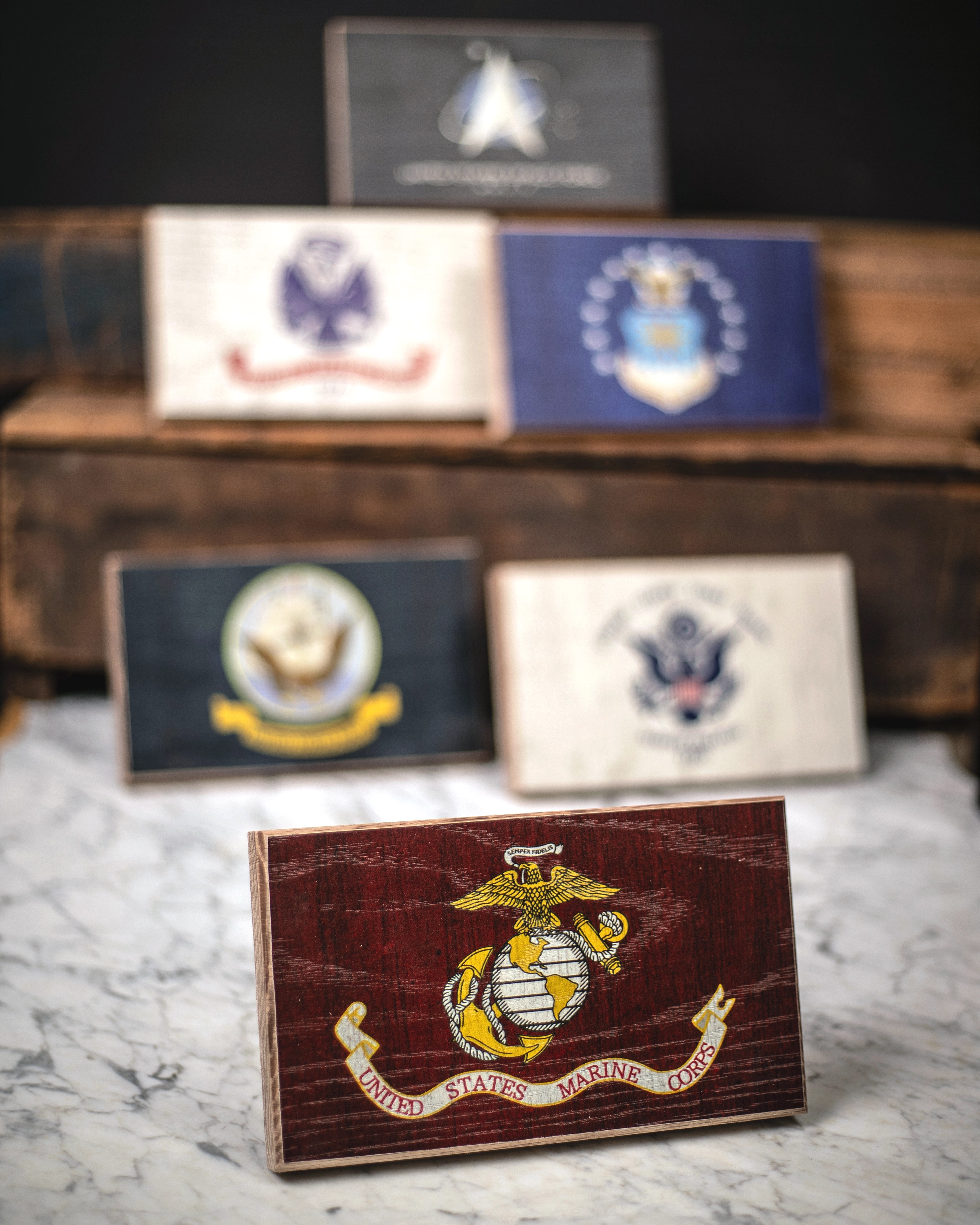 Collection of U.S. military service branch desk flags featuring U.S. Marine Corps sitting on marble surface.