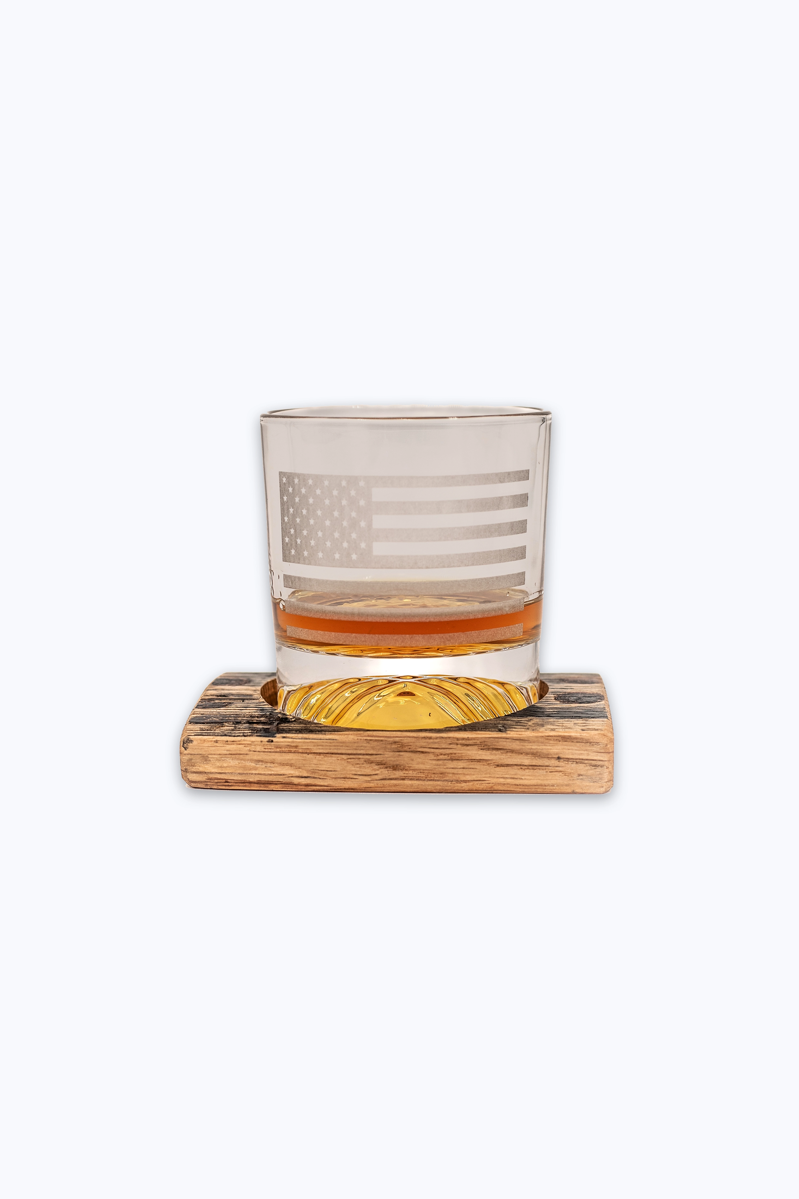 Rocks glass with American flag design on a bourbon barrel wooden coaster