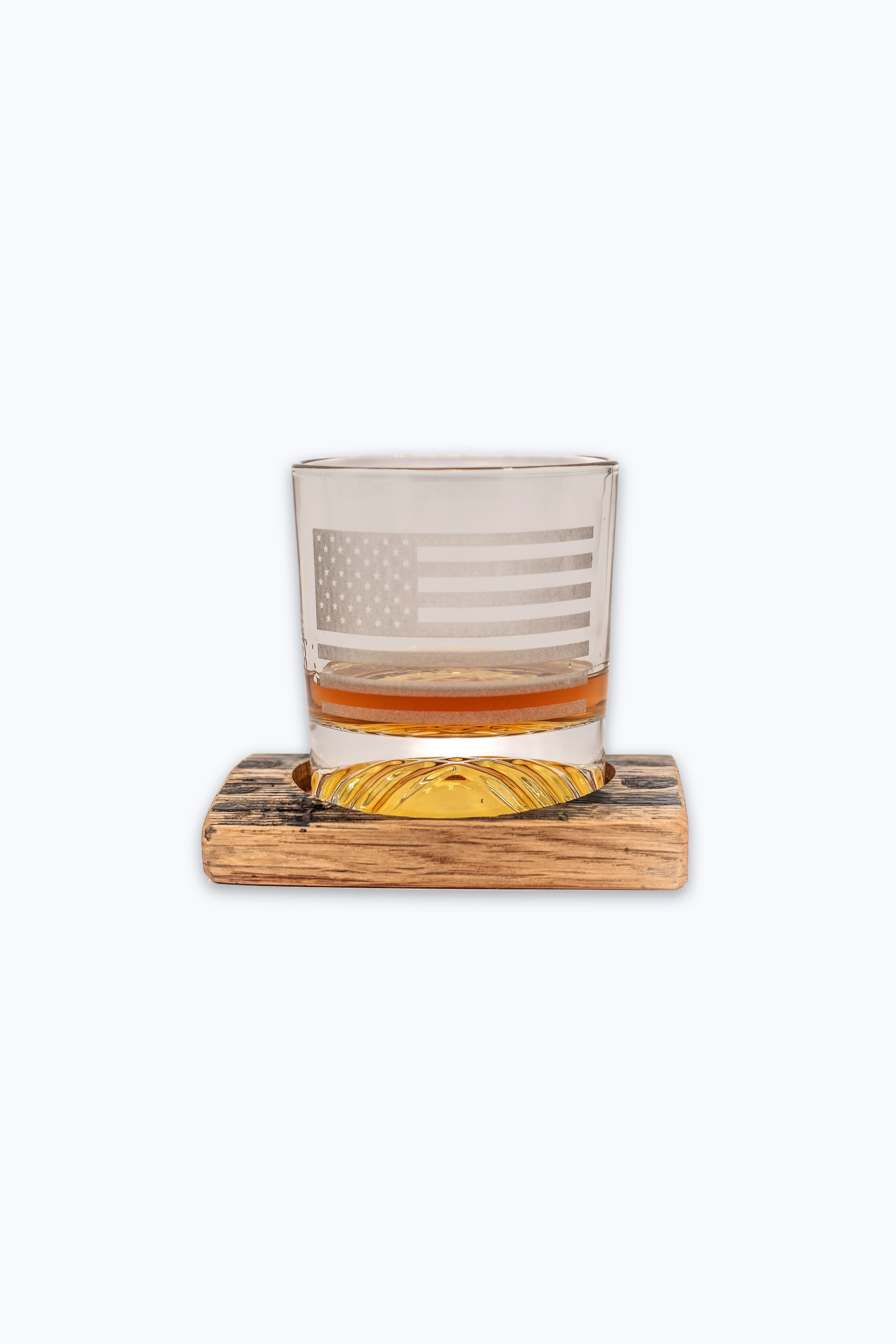 Rocks glass with American flag design on a bourbon barrel wooden coaster