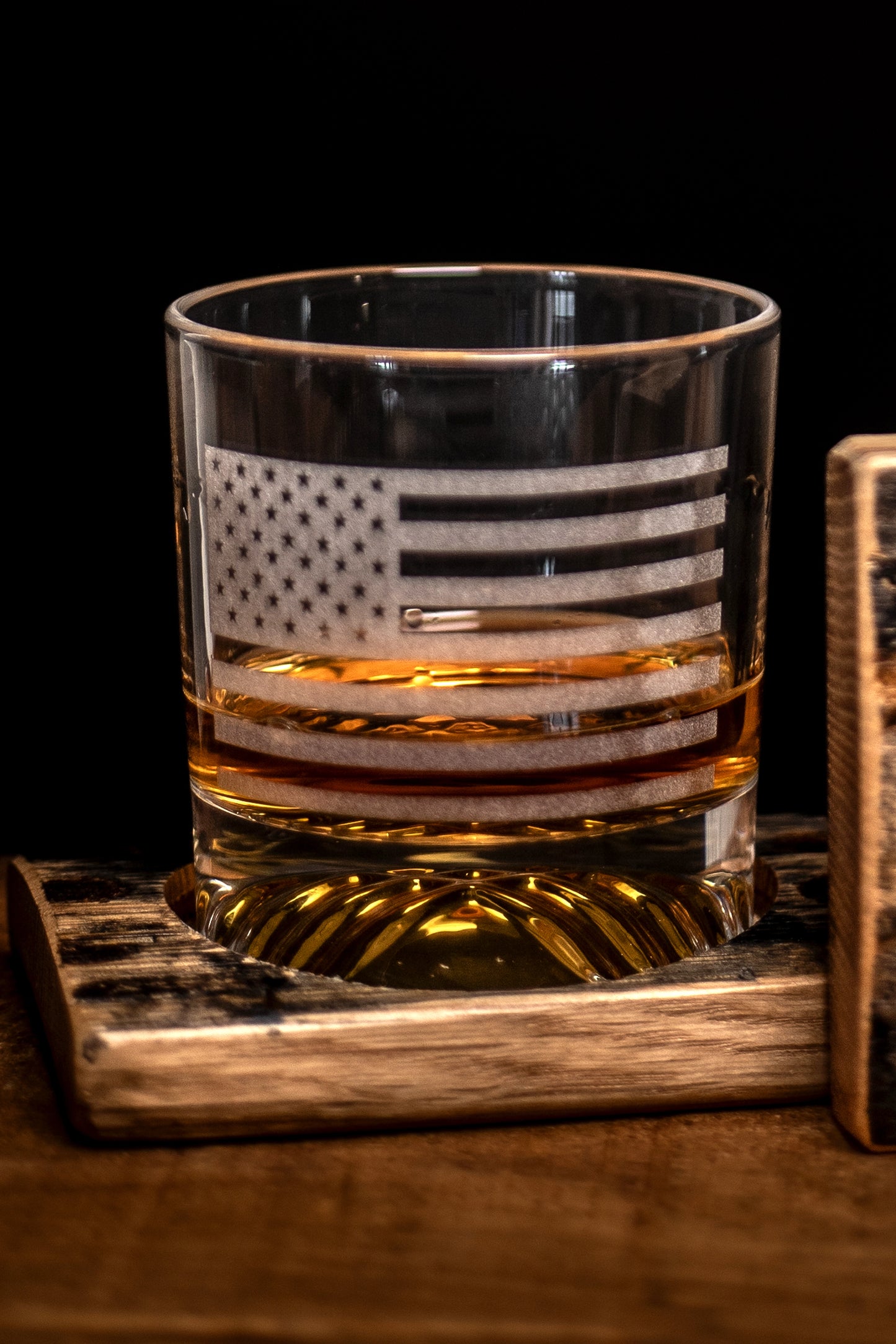 Rocks glass with American flag design filled on a bourbon barrel wooden coaster