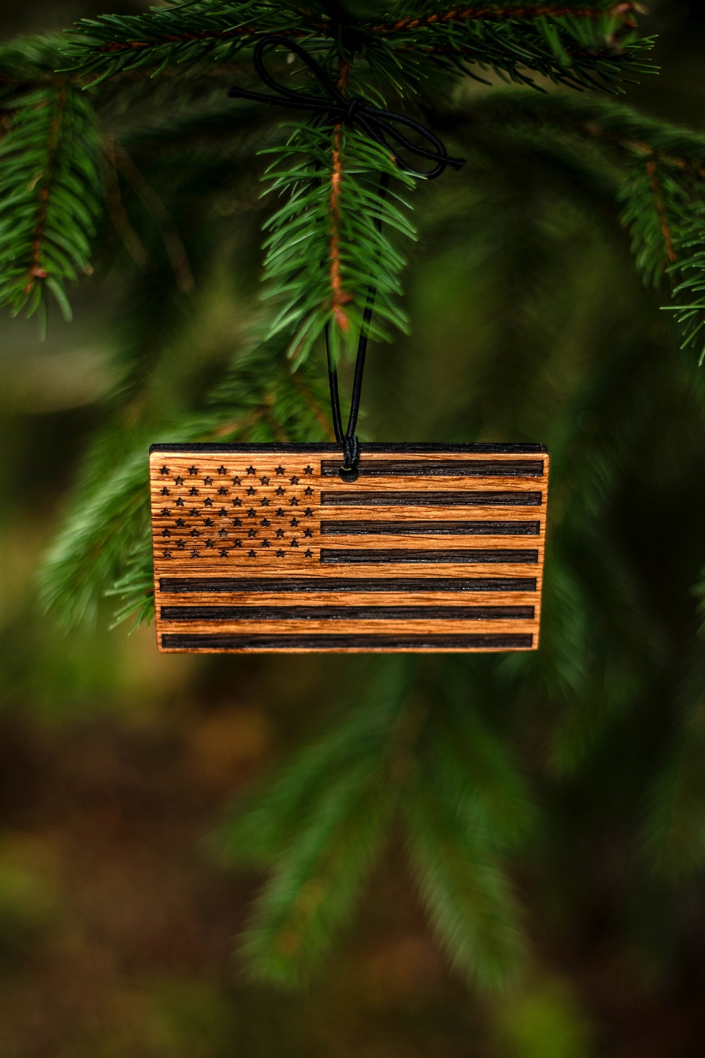 Wooden bourbon barrel American flag ornament hanging on a tree branch