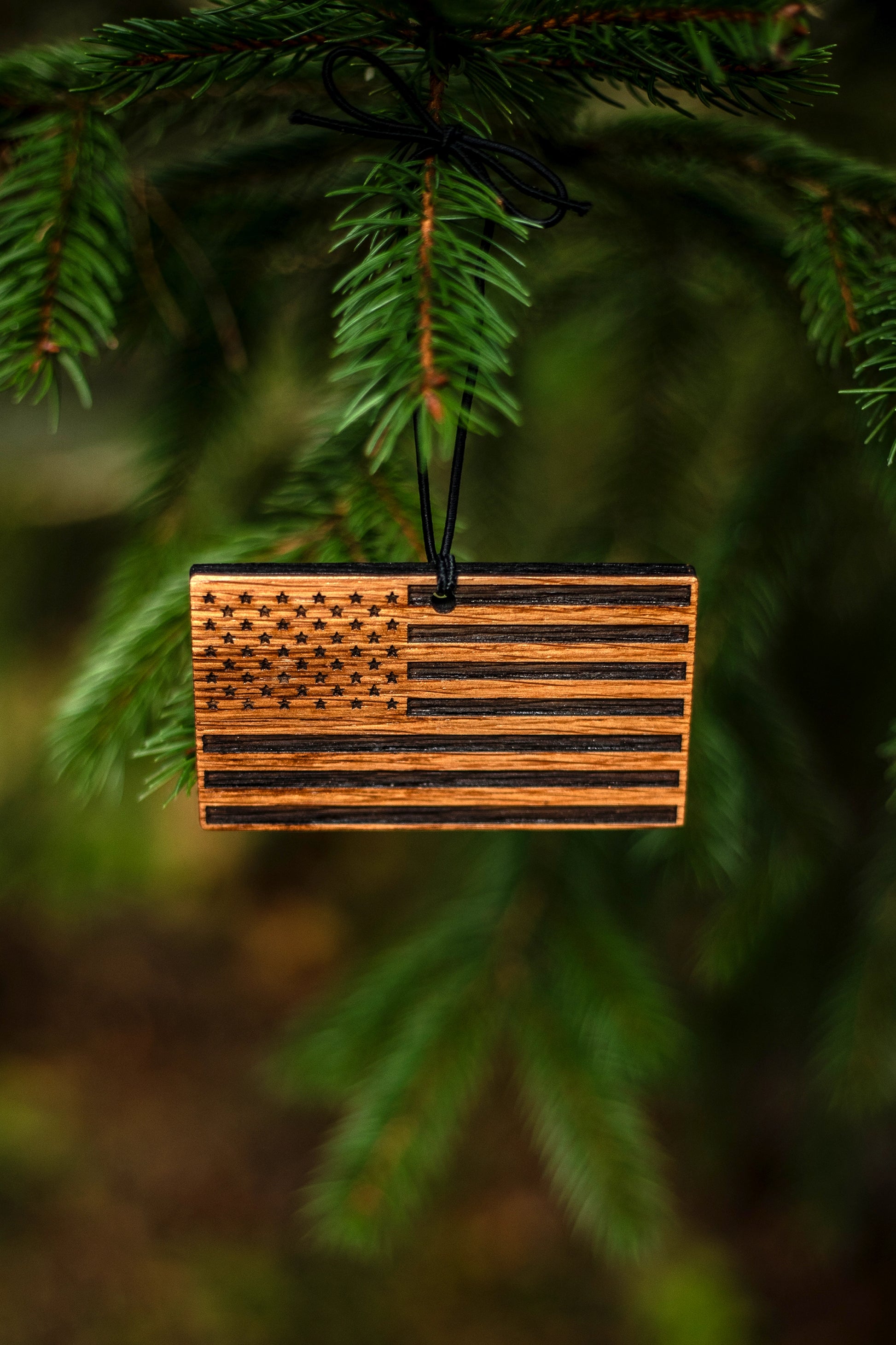 Wooden bourbon barrel American flag ornament hanging on a tree branch