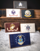 Collection of U.S. military service branch desk flags featuring U.S. Air Force sitting on marble surface.