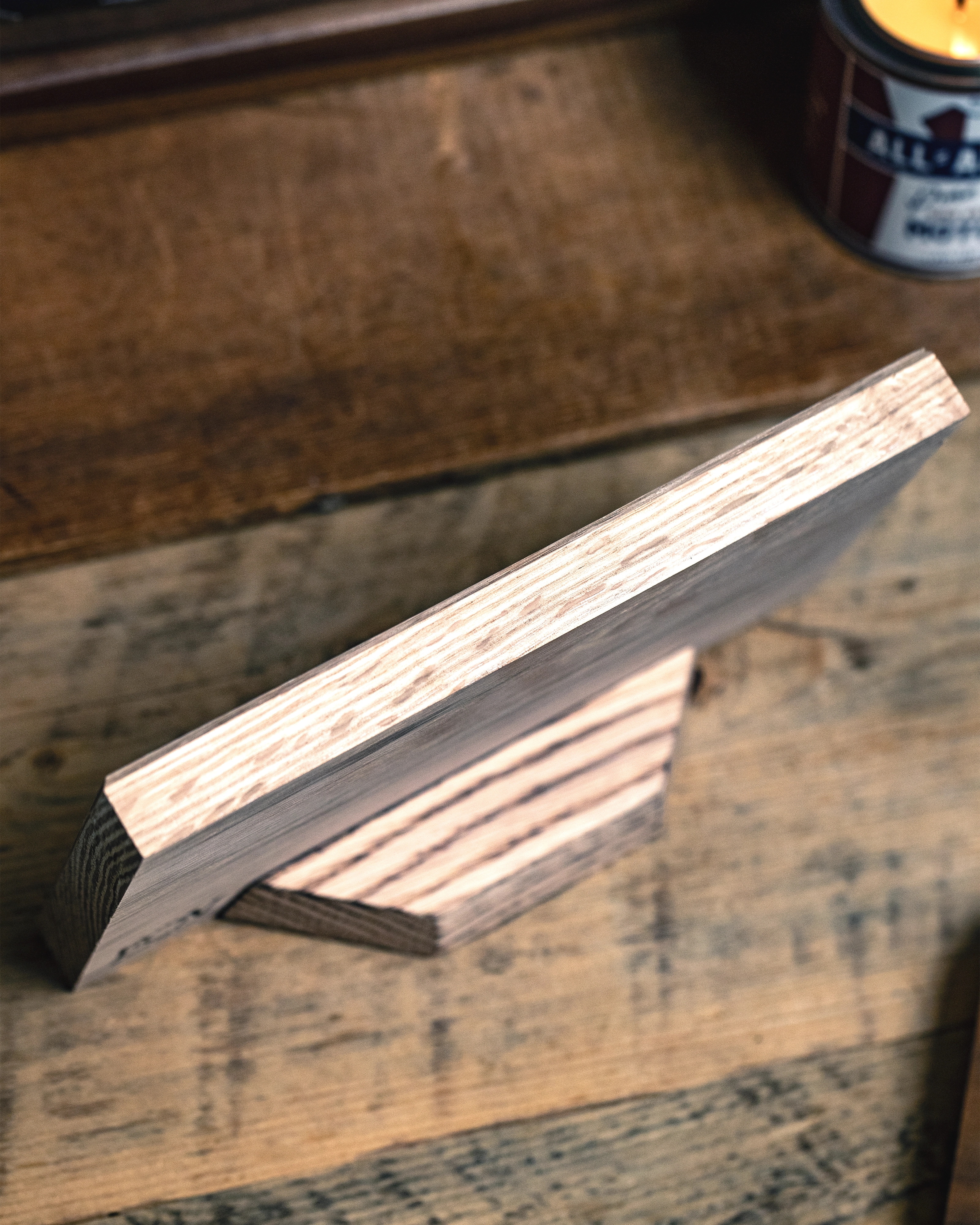 Back of U.S. military service branch Air Force desk flag sitting on wooden surface with a candle in the background.