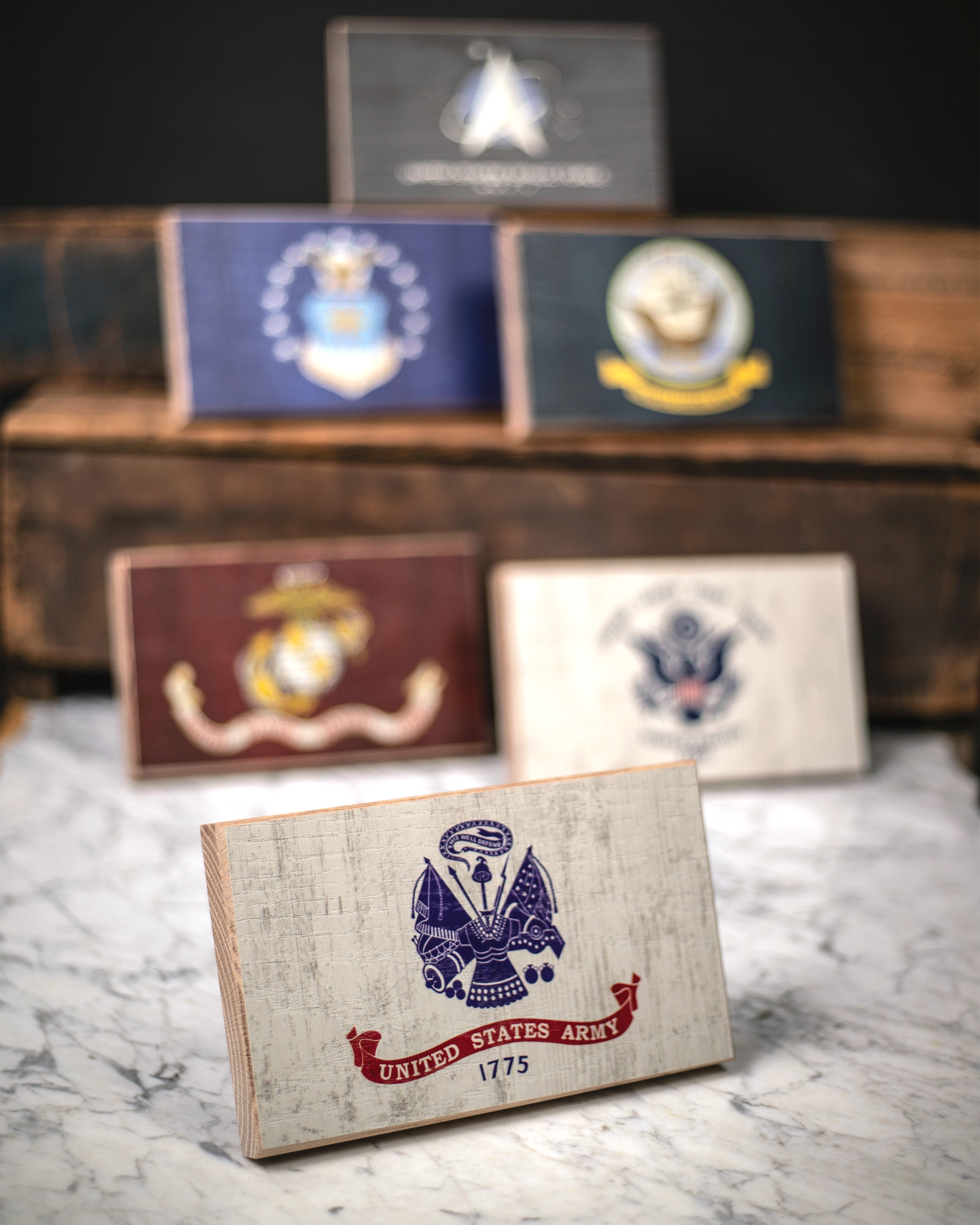 Collection of U.S. military service branch desk flags featuring U.S. Army sitting on marble surface.