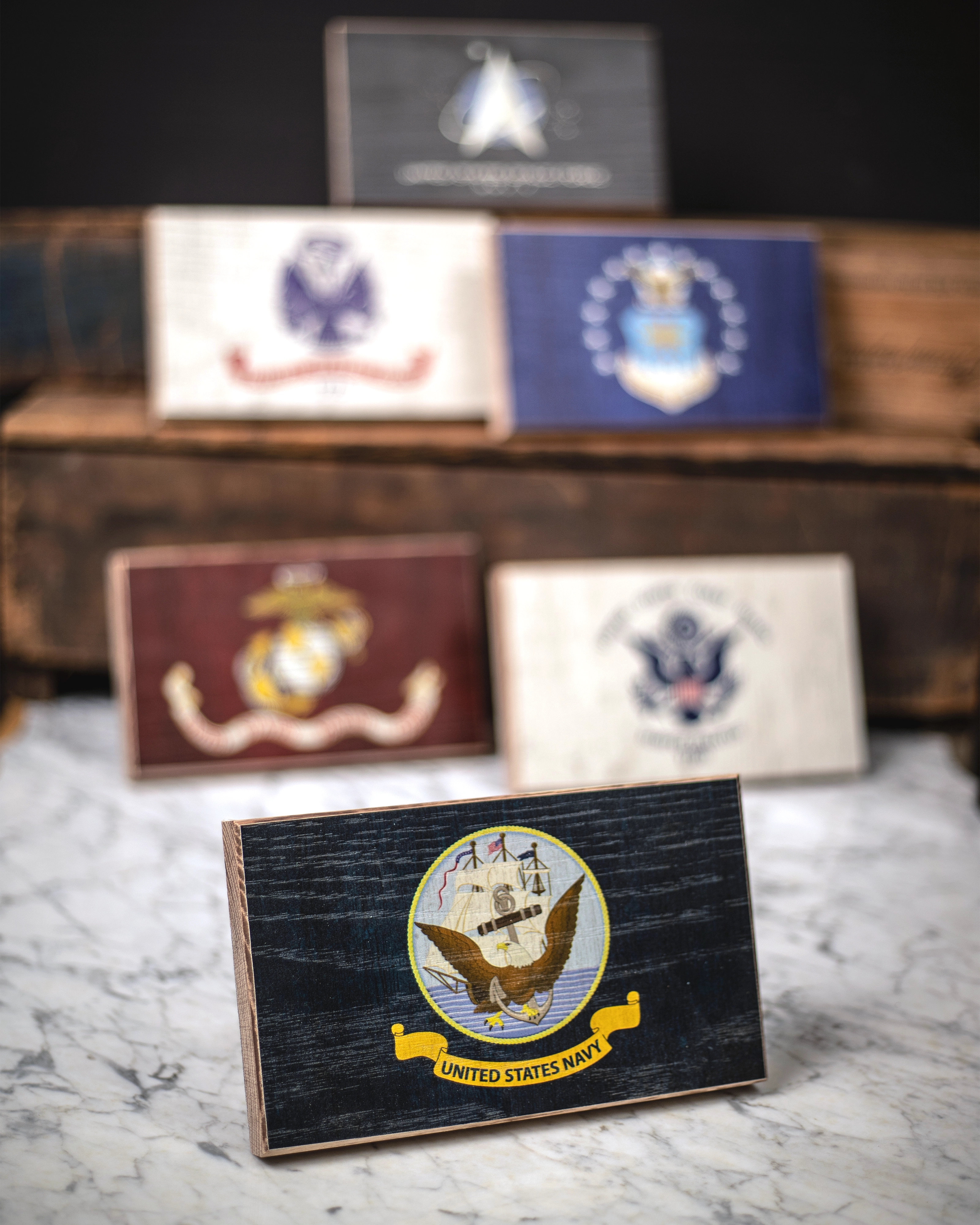 Collection of U.S. military service branch desk flags featuring U.S. Navy sitting on marble surface.